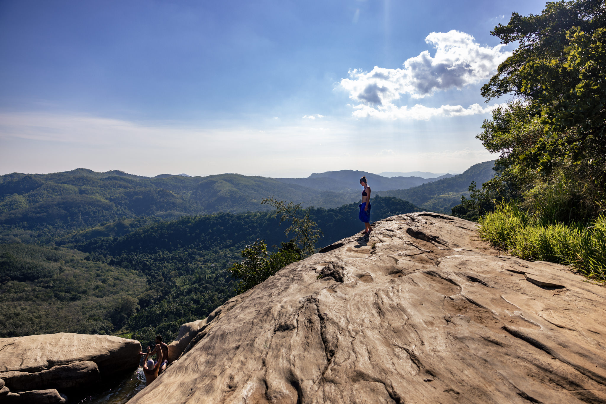 Woman walks across the rocks at Diyaluma Falls