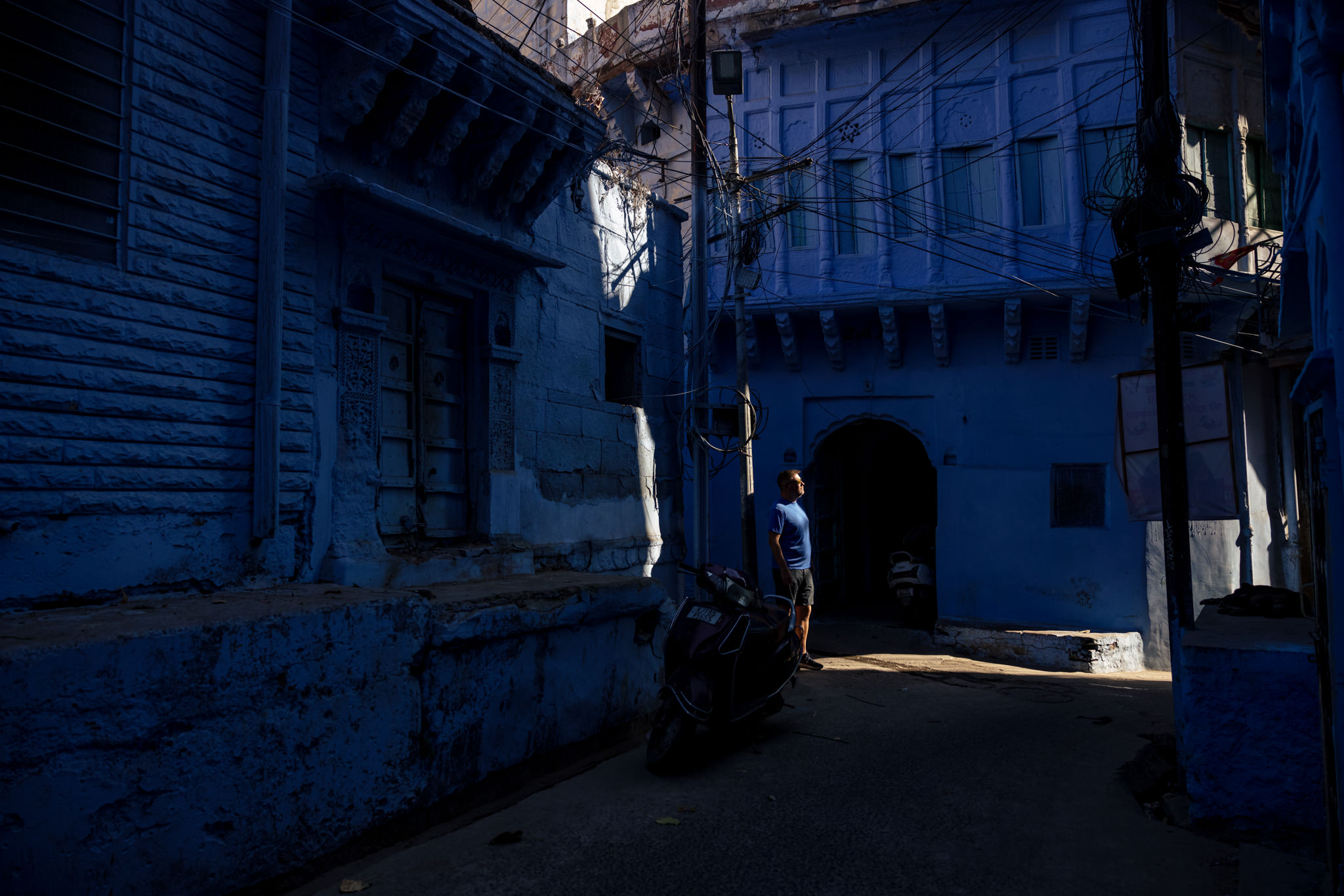 Man stands in patch of sunshine in Jodhpur blue laneway