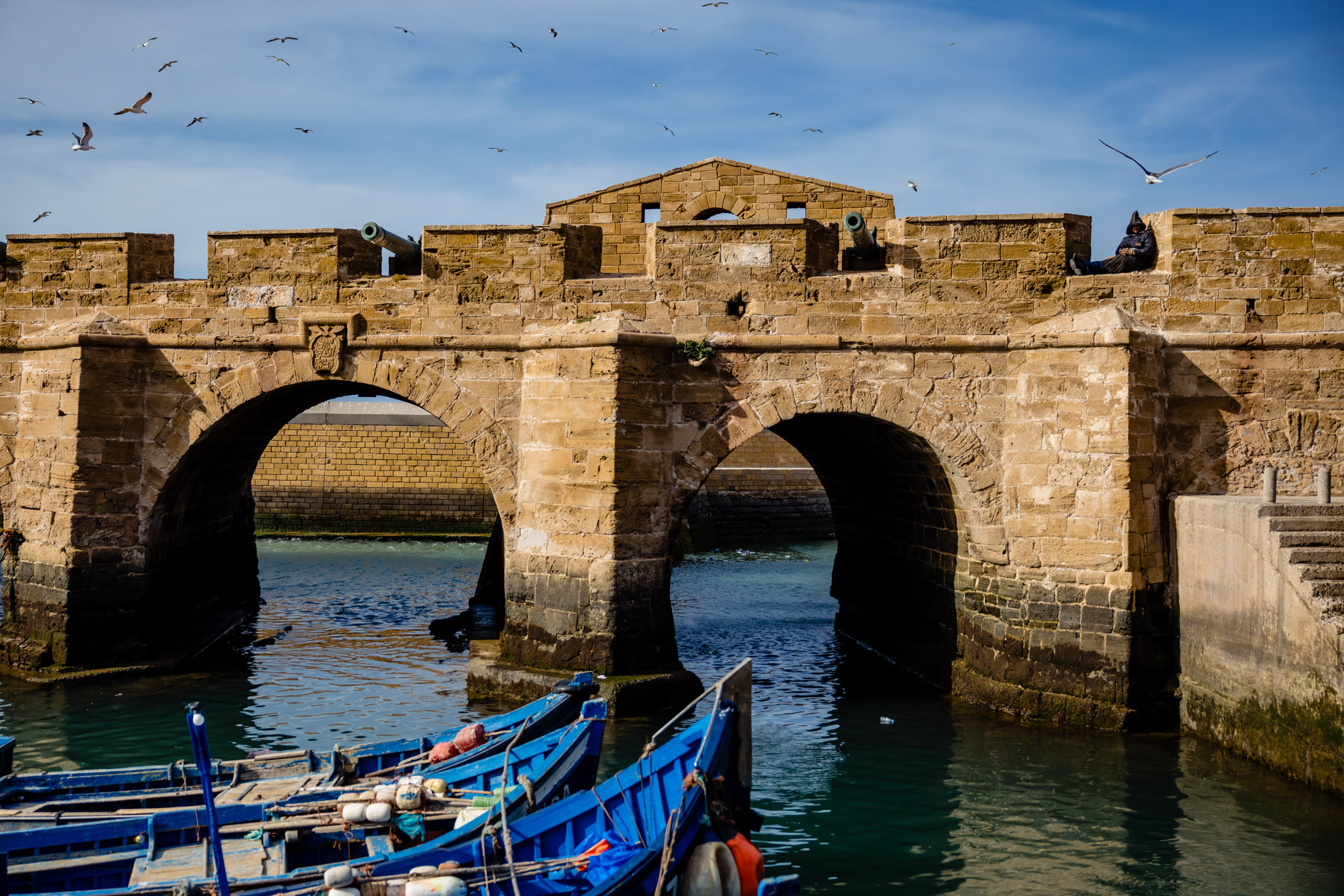 a man dozes between the turrets of Essaouira's city walls