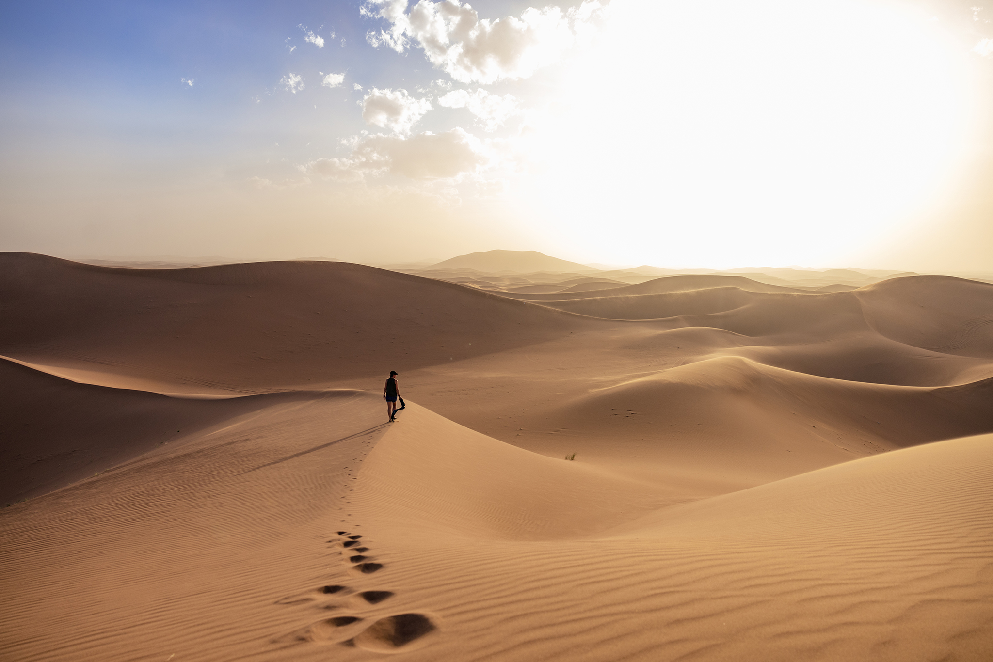 Woman walks on Erg Chigaga sand dune in Morocco Sahara Desert
